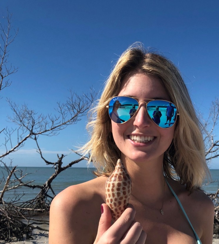 a, woman, smiles, while, holding, shell, at, the, beach Everglades Boattours A Woman Smiles While Holding