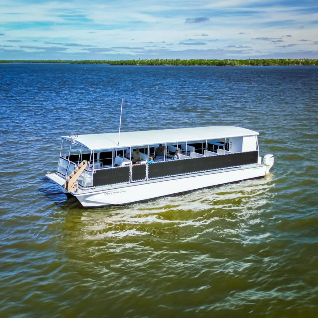 A large white boat with a covered seating area glides through blue water. Evergladesnationalparkadventures Ten Thousand Islands Boat Tour